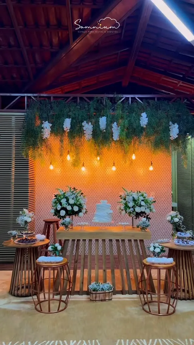 Decoração de evento com flores brancas, luzes aconchegantes e mesa de doces